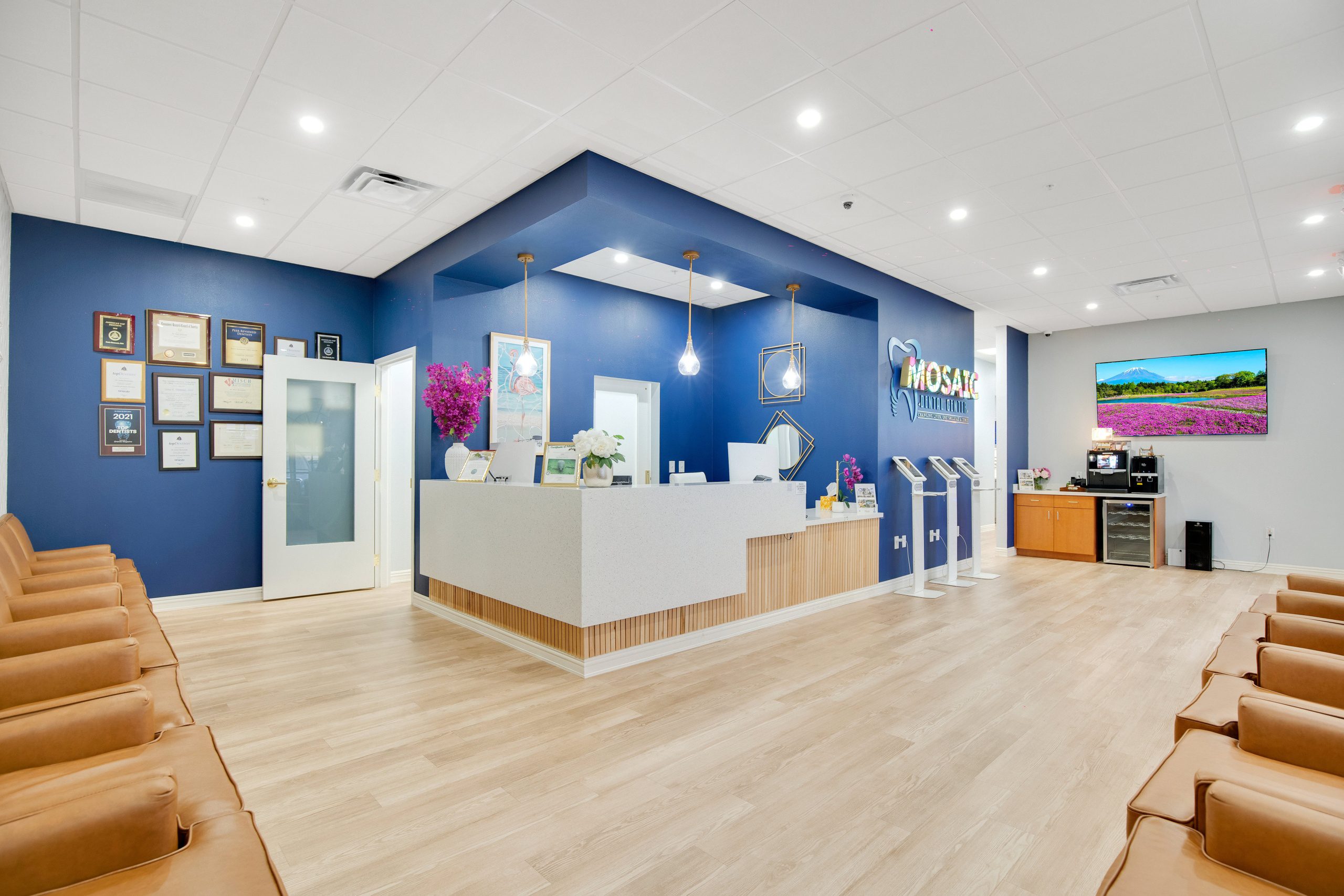 Blue accent wall behind the desk displaying a logo and framed certificates.